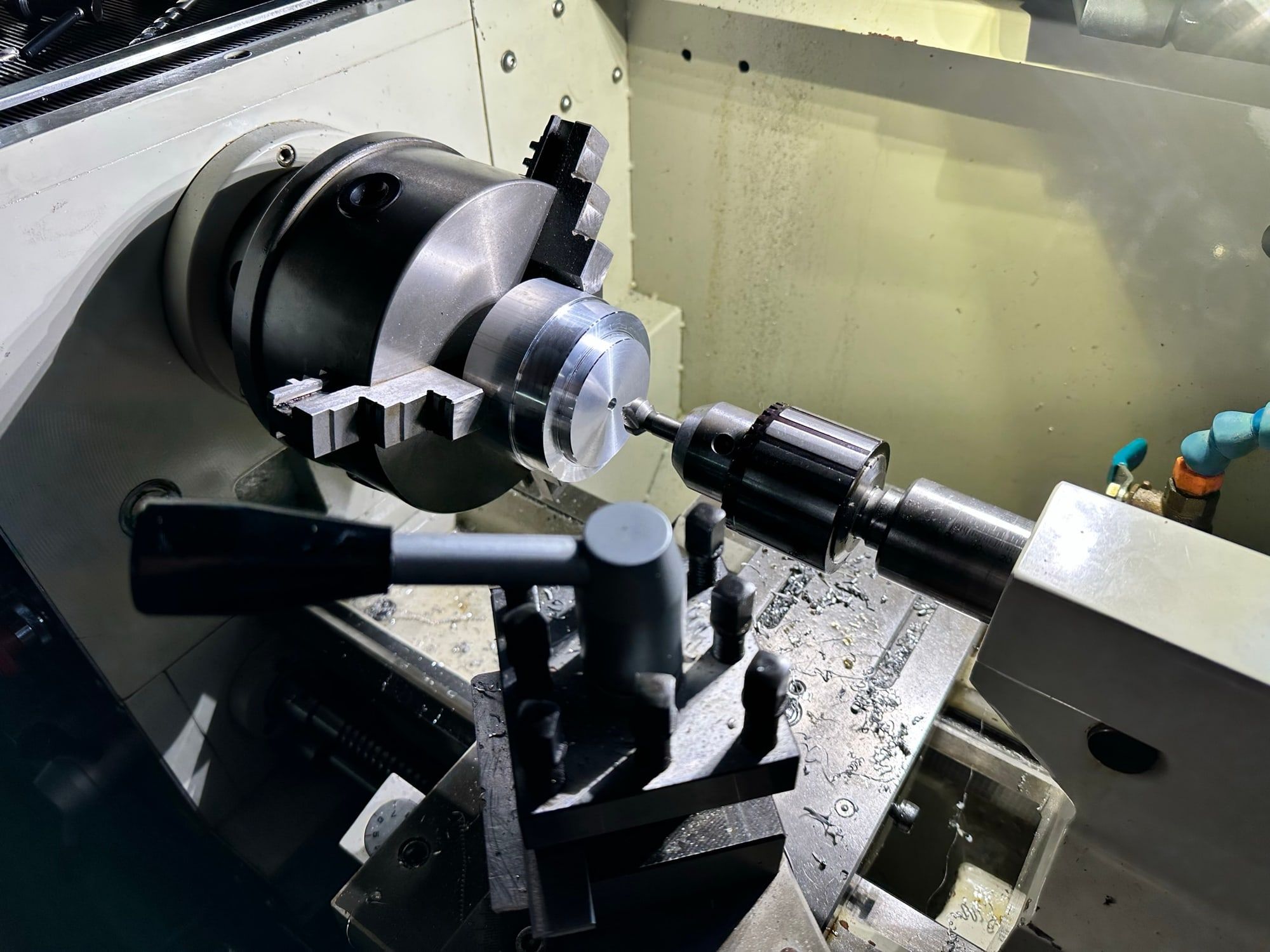 An aluminium part being turned on a lathe in the workshop